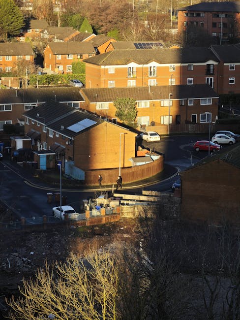 An aerial view of a residential area in Purfleet RM19, featuring a group of brown brick buildings and multi-storey apartment blocks. In the foreground, there is a small, single-story brick structure w